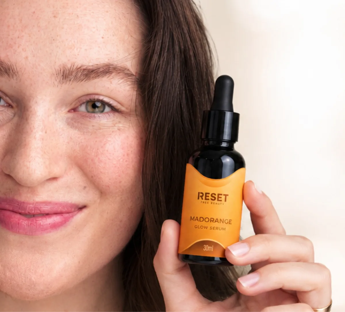 Primer plano de una mujer con el frasco de Madorange junto al rostro